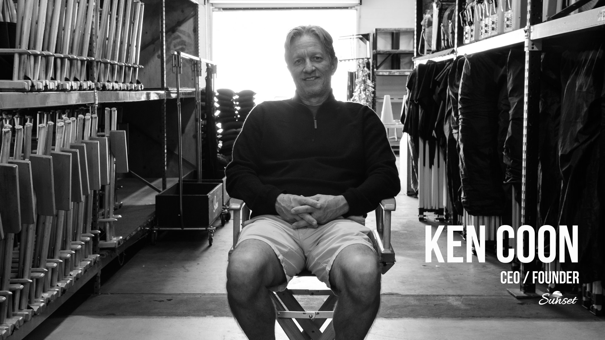 Ken Coon, COO and Founder, seated in a director's chair inside the Sunset warehouse