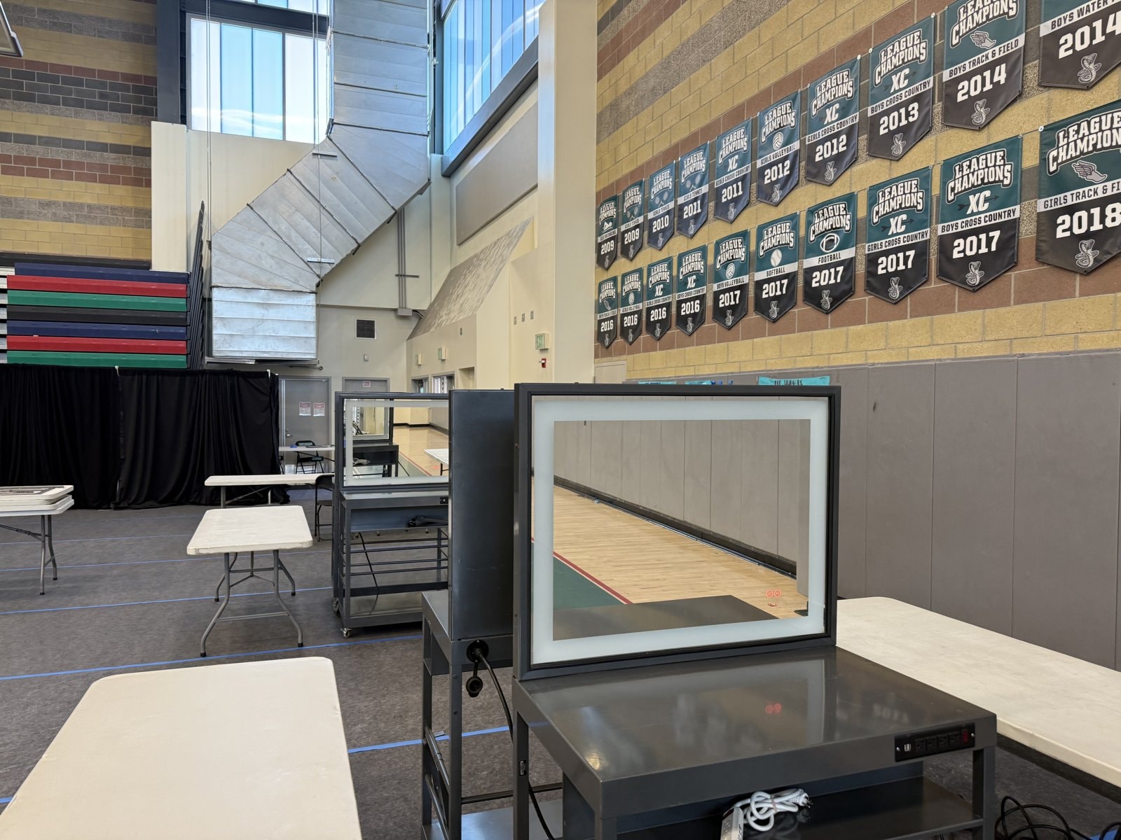 Hair and makeup stations set up inside a school gymnasium