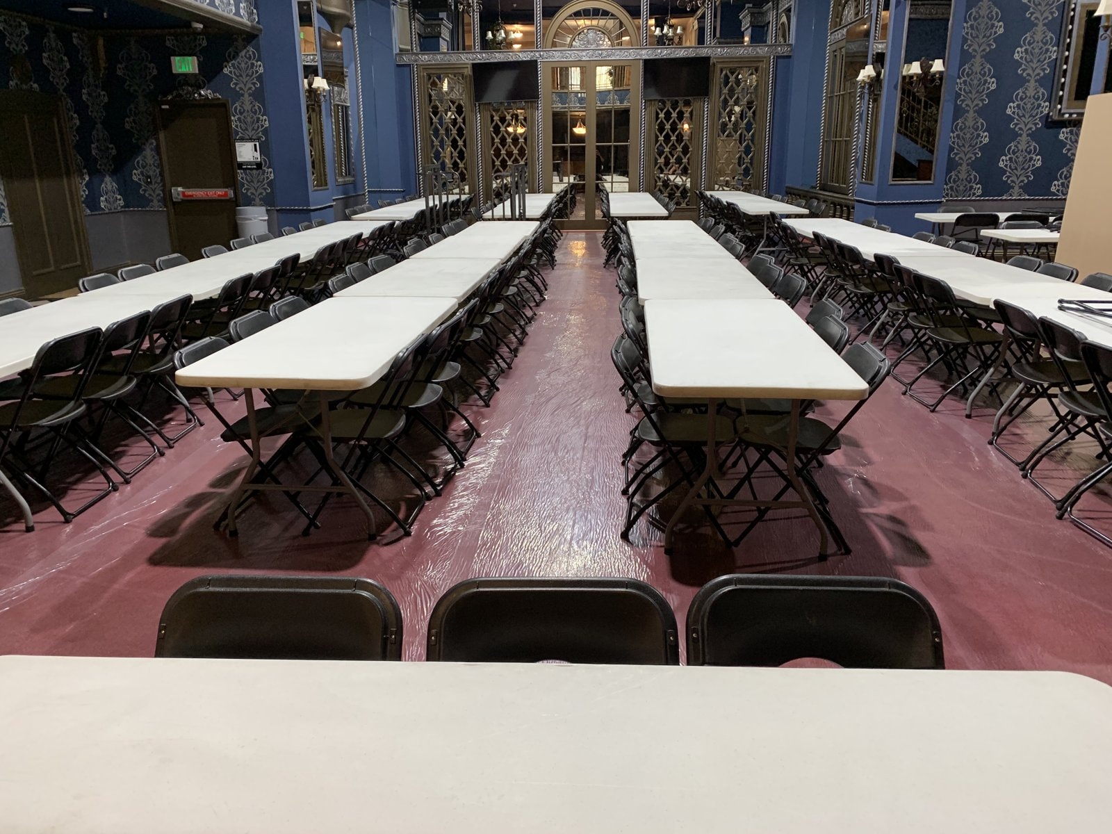 Long tables and chairs set up inside an ornate ballroom-style interior for a production lunch